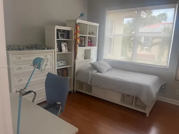 a bedroom with a bed wooden floor and windows