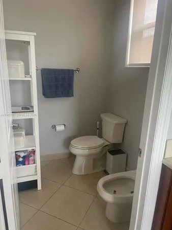 a white toilet sitting next to a bathroom sink and a window