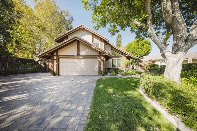 a view of a wooden house with a yard and large trees
