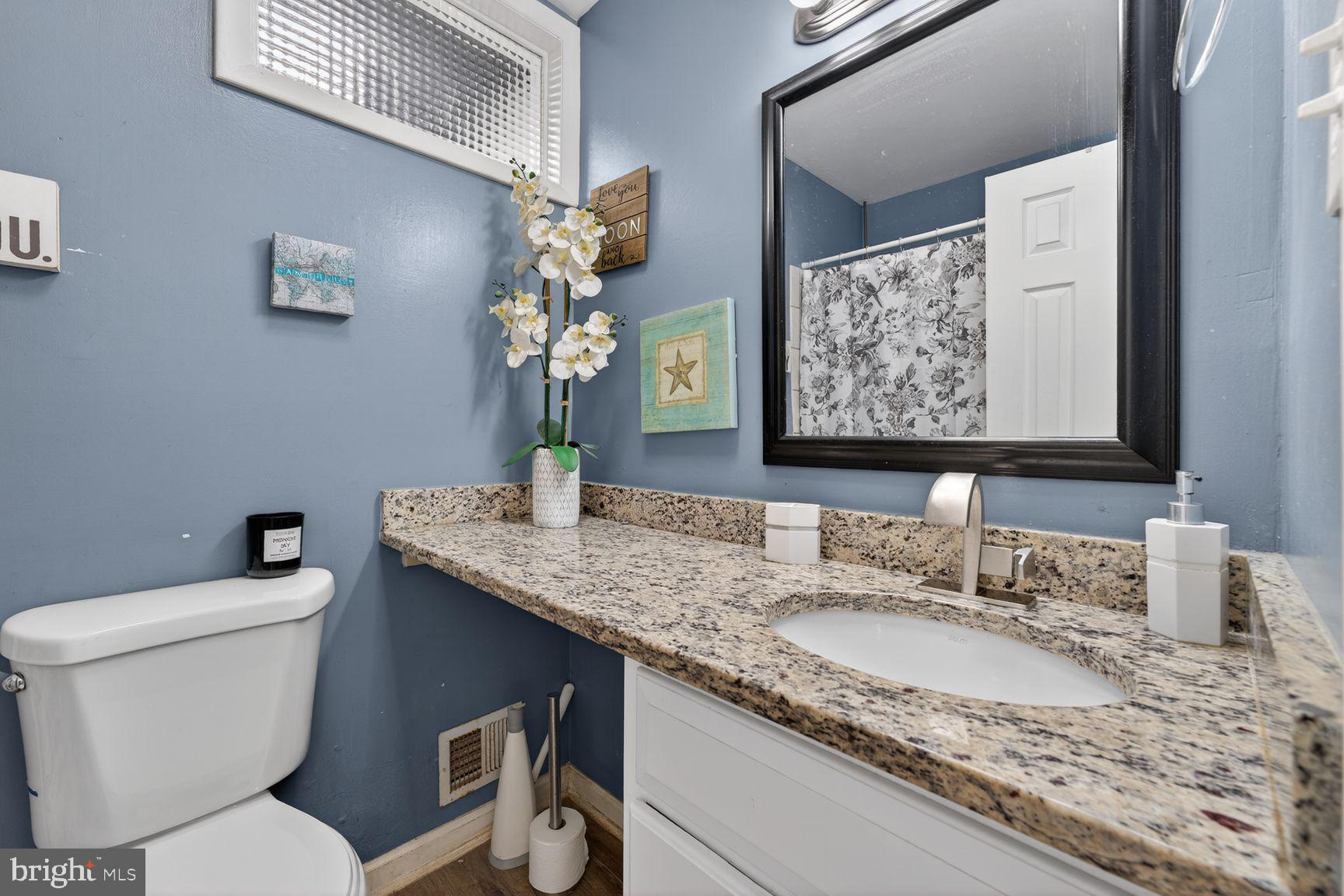 1104 Caddington Avenue Silver Spring, MD 20901 - Photo 11 of 35 a bathroom with a granite countertop toilet sink and mirror