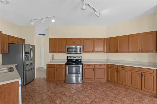 a kitchen with stainless steel appliances granite countertop a stove top oven a sink dishwasher a refrigerator and cabinets with wooden floor