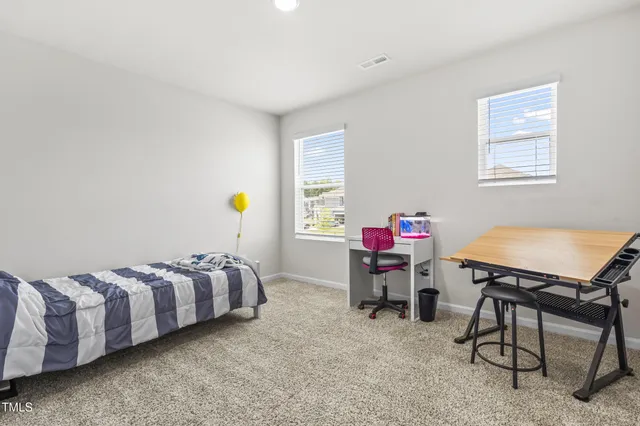a spacious bedroom with a bed a couch and a flat tv screen on dresser