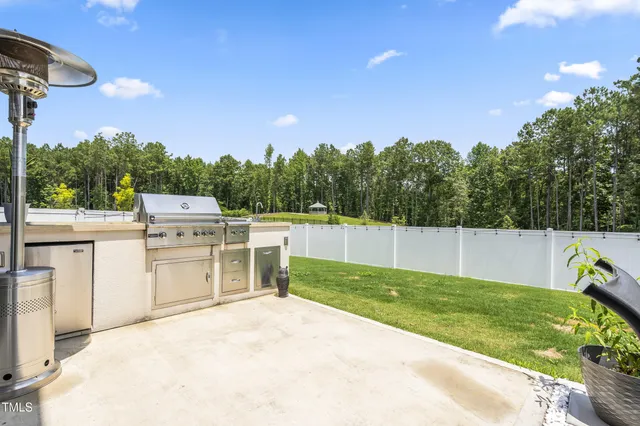 a kitchen with stainless steel appliances granite countertop a sink a stove a refrigerator and white cabinets with wooden floor