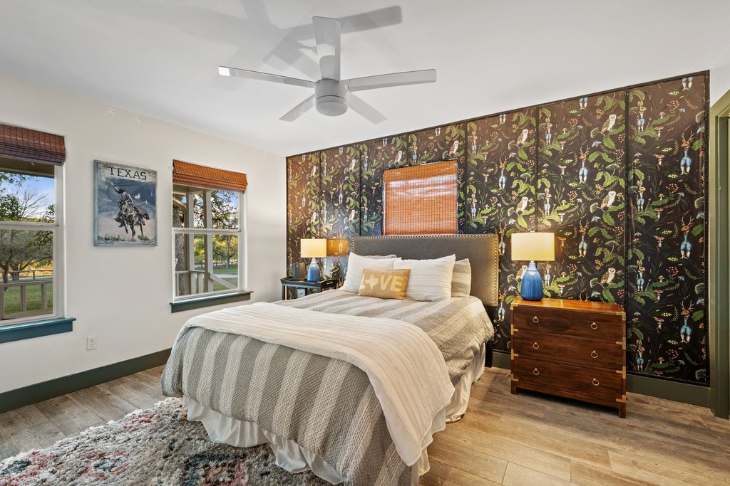 2800 River Road Wimberley, TX 78676 - Photo 20 of 40 Bedroom featuring wallpapered walls, light wood-type flooring, an accent wall, and ceiling fan