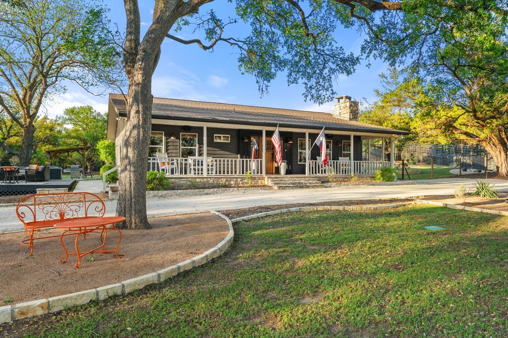2800 River Road Wimberley, TX 78676 - Photo 3 of 38 Ranch-style exterior with a deep covered porch, stone-faced foundation, and a prominent stone chimney