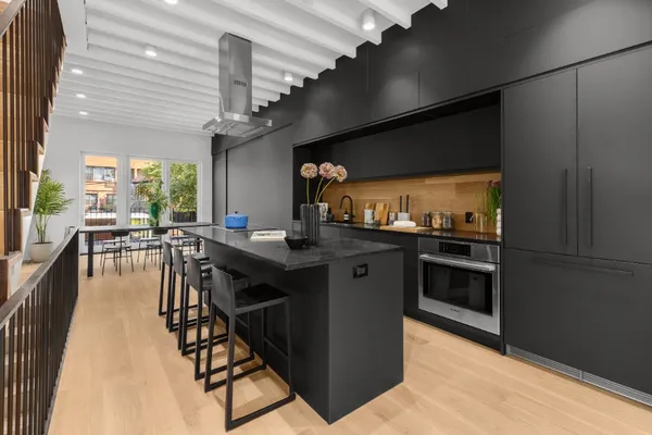 a kitchen with stainless steel appliances kitchen island granite countertop a stove a refrigerator a dining table and chairs with wooden floor