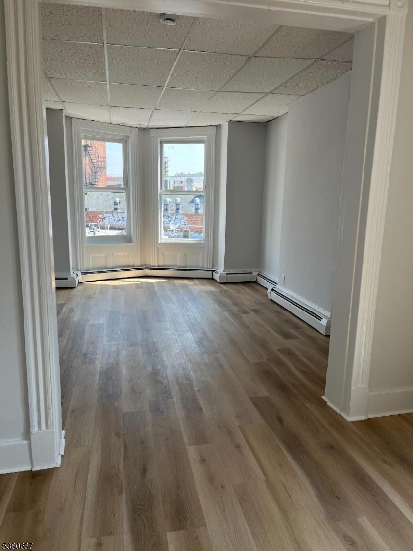 304 Morris Avenue Elizabeth, NJ 07208 - Photo 3 of 9 an empty room with wooden floor and windows