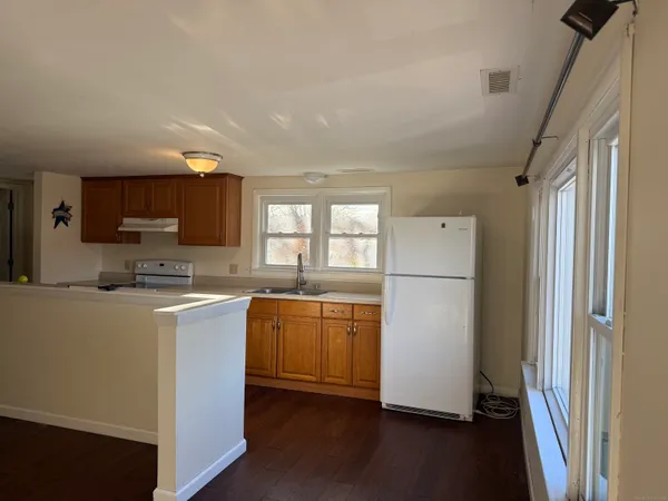 a kitchen with stainless steel appliances granite countertop a refrigerator a sink dishwasher a stove top oven a dining table and chairs with wooden floor