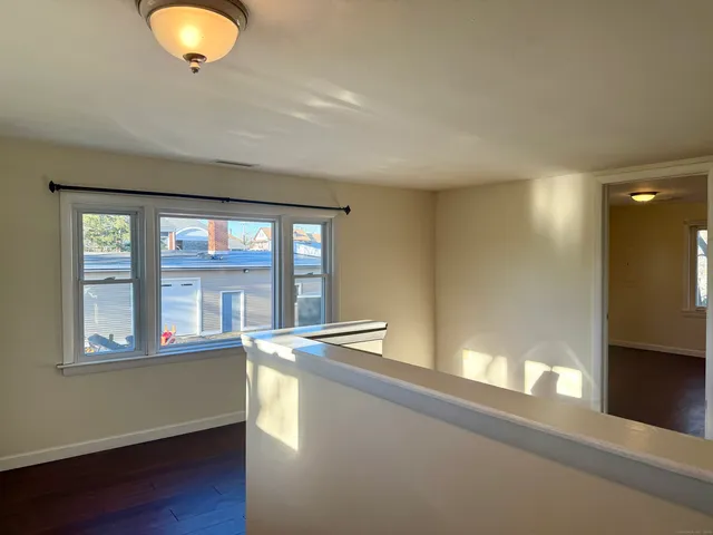 an empty room with wooden floor closet and windows