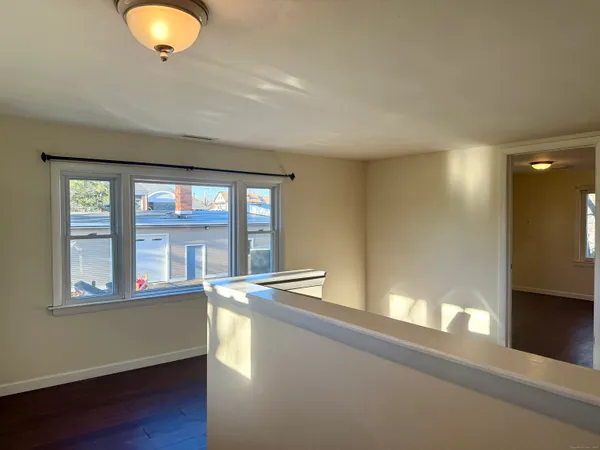 an empty room with wooden floor closet and windows
