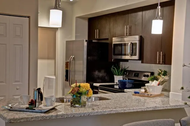 a kitchen with kitchen island granite countertop a sink and a stove top oven