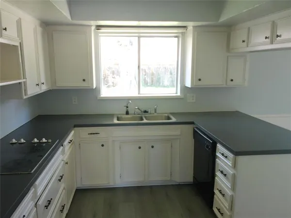 a kitchen with granite countertop a sink a stove and cabinets