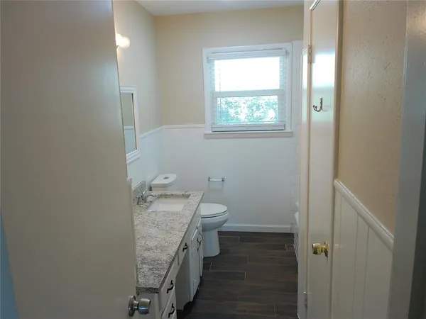 a bathroom with a granite countertop toilet a sink and mirror