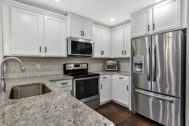 a kitchen with granite countertop white cabinets and white appliances