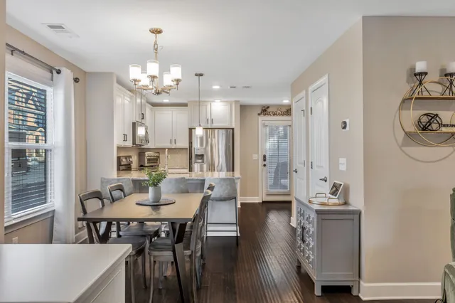 a kitchen with kitchen island a dining table chairs stainless steel appliances and cabinets