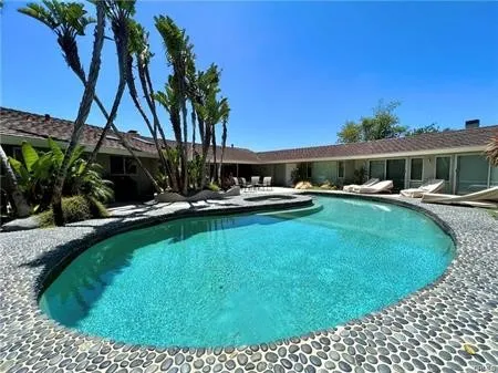 a view of swimming pool with outdoor seating and house in the background