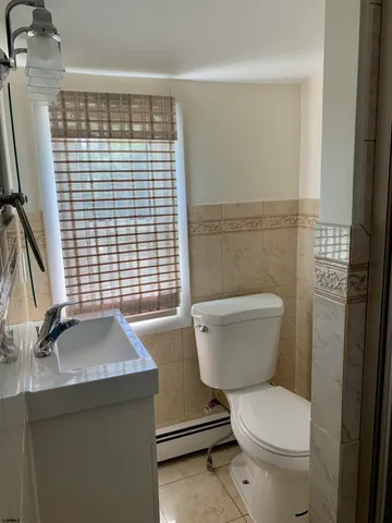 a bathroom with a granite countertop toilet a sink and a window