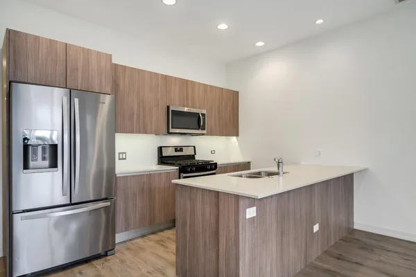 a kitchen with kitchen island a refrigerator stove microwave and sink