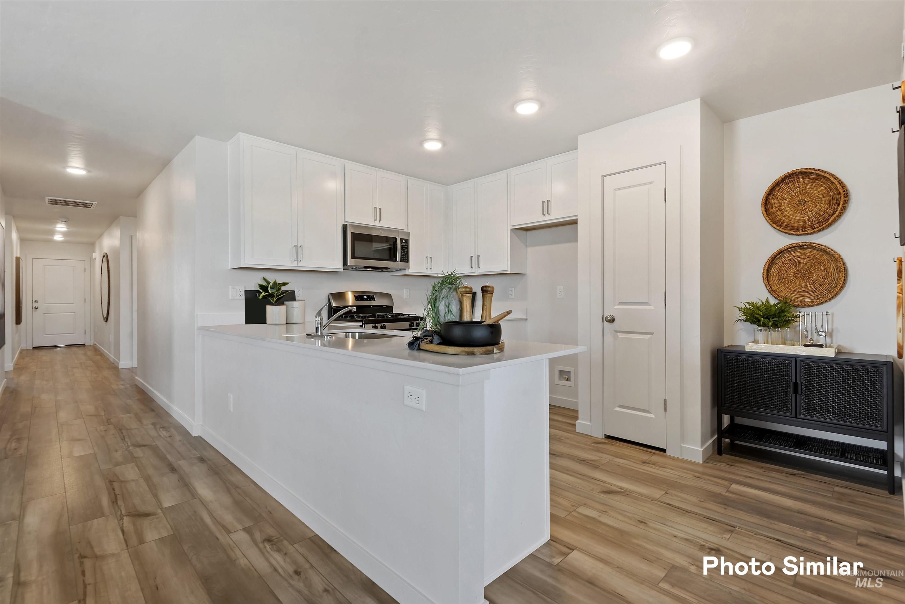 15182 Cumulus Way Caldwell, ID 83607 - Photo 7 of 26 Kitchen with white cabinets, a peninsula, light wood-style flooring, stainless steel appliances, and recessed lighting