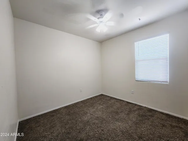 an empty room with a chandelier fan and windows