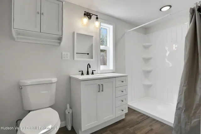 a bathroom with a toilet a sink a mirror and shower