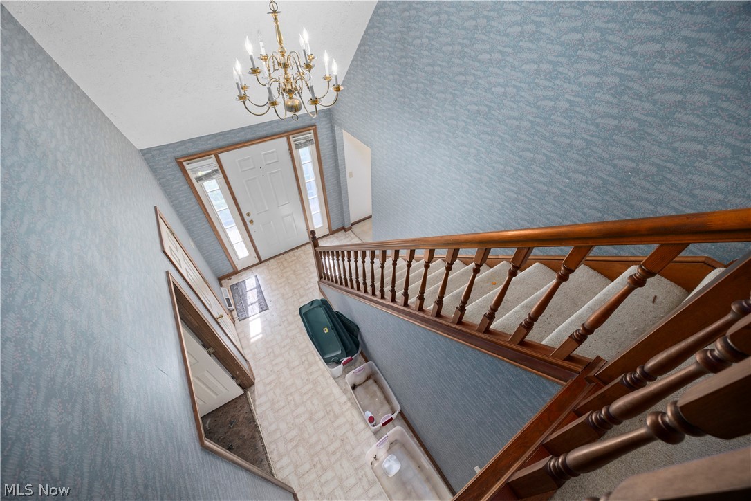 722 Jaycox Road Avon Lake, OH 44012 - Photo 28 of 48 Foyer with a white entry door featuring sidelight windows, a brass chandelier, and wood-finish staircase railing