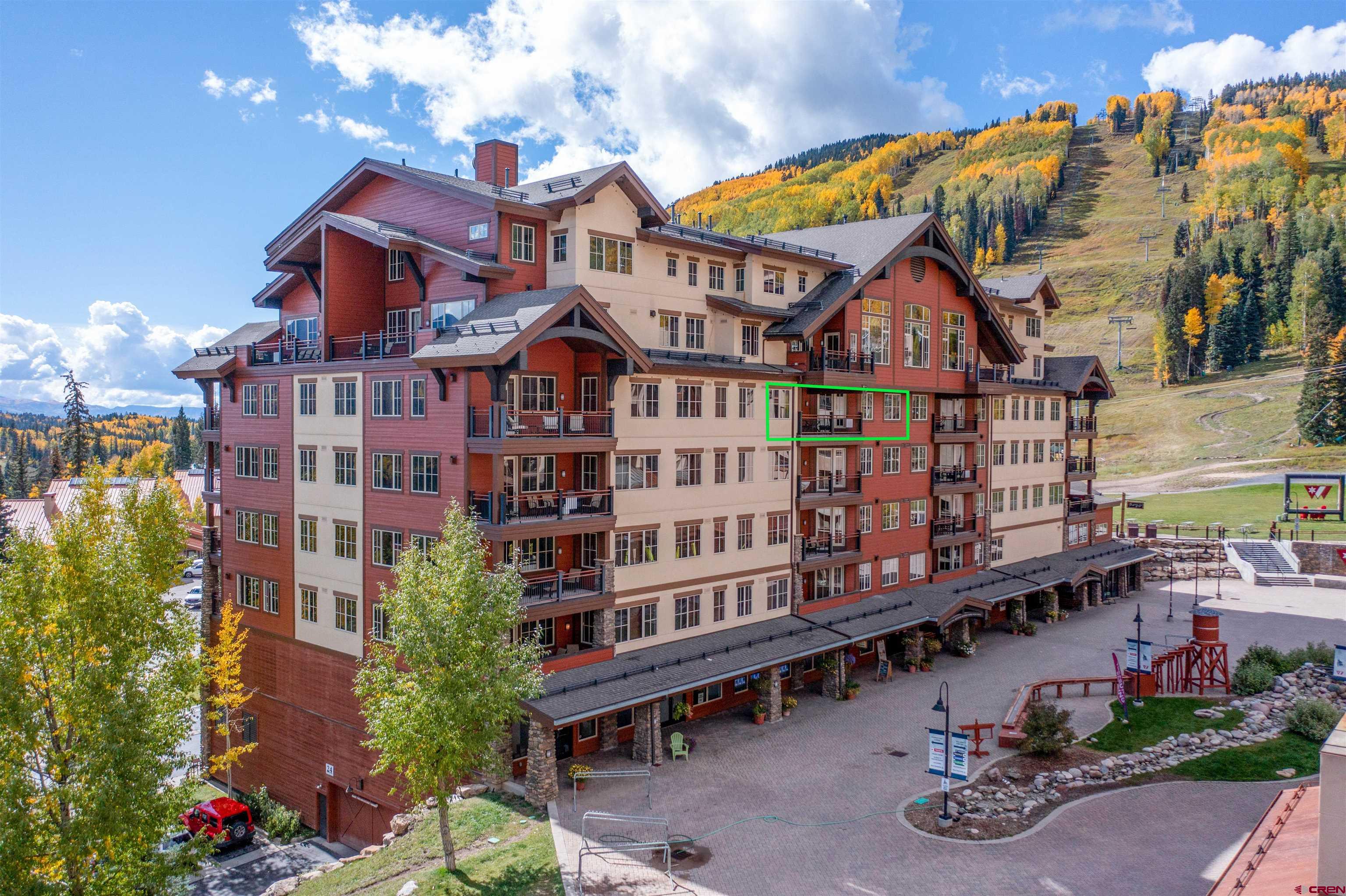 a view of a brick house with many windows and plants