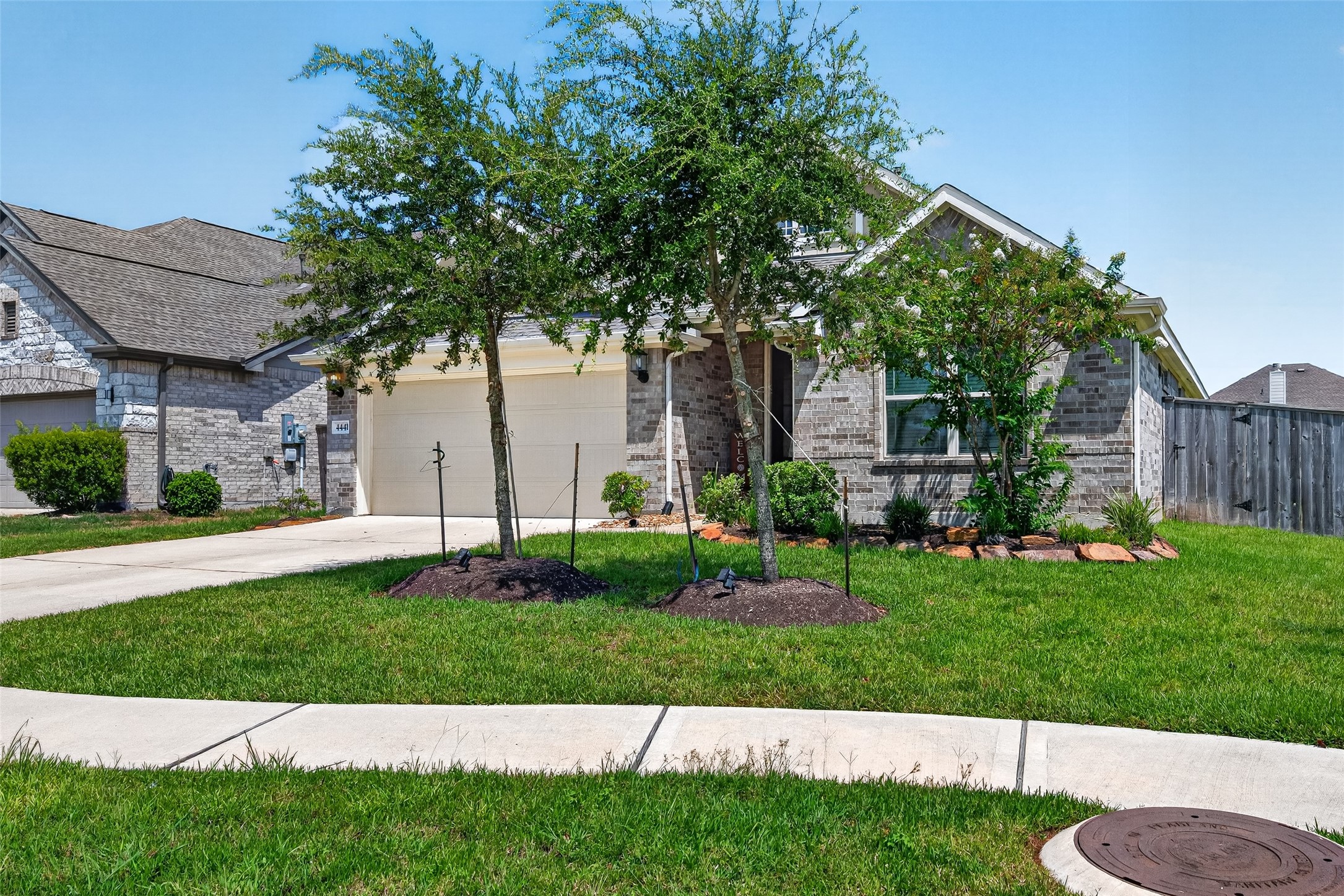 A spacious lawn stretches across the front of the property, giving the home an open, welcoming presence. Young trees and garden beds add greenery while leaving plenty of room to enjoy the yard.