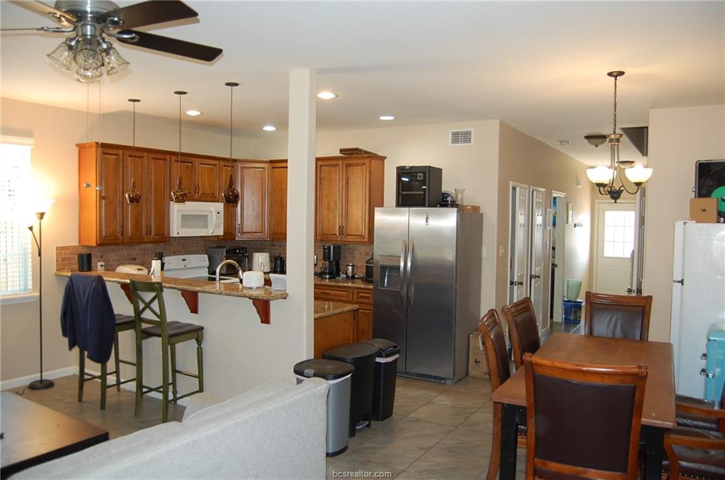 300 Ash Street, Unit B College Station, TX 77840 - Photo 3 of 23 a kitchen with stainless steel appliances kitchen island granite countertop a refrigerator a stove a sink dishwasher a dining table and chairs with wooden floor
