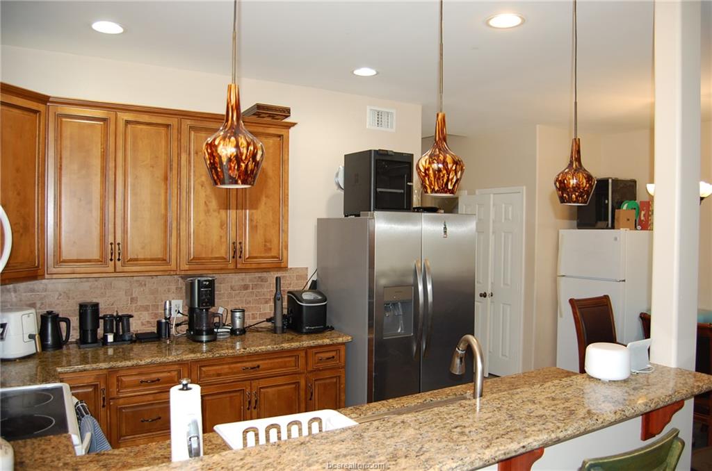 300 Ash Street, Unit B College Station, TX 77840 - Photo 5 of 23 a kitchen with stainless steel appliances kitchen island granite countertop a refrigerator a stove and a sink with wooden floor