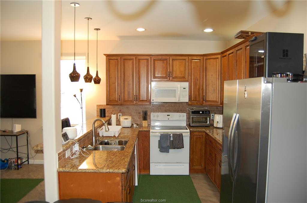300 Ash Street, Unit B College Station, TX 77840 - Photo 6 of 23 a kitchen with stainless steel appliances granite countertop a refrigerator a stove and a sink with wooden floor