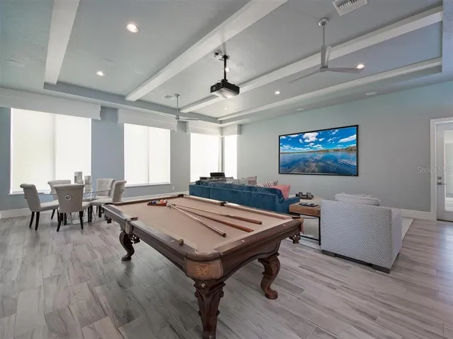 a room with furniture pool table wooden floor and windows