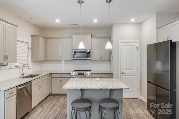 a kitchen with stainless steel appliances a sink a stove a refrigerator and cabinets