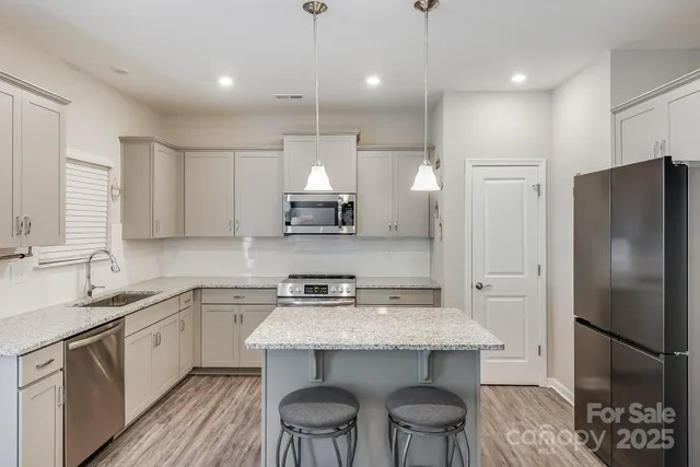 a kitchen with stainless steel appliances a sink a stove a refrigerator and cabinets