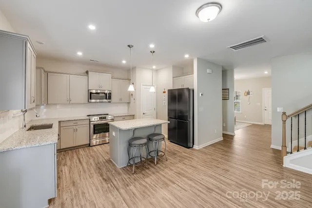 a large kitchen with a center island wooden floor stainless steel appliances and cabinets