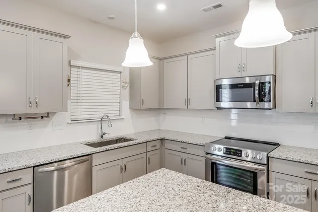 a kitchen with granite countertop a sink stainless steel appliances and cabinets