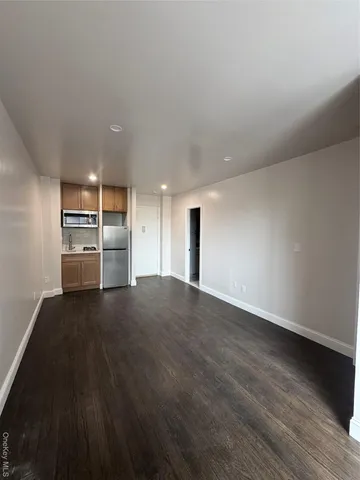 a view of an empty room with a kitchen and wooden floor