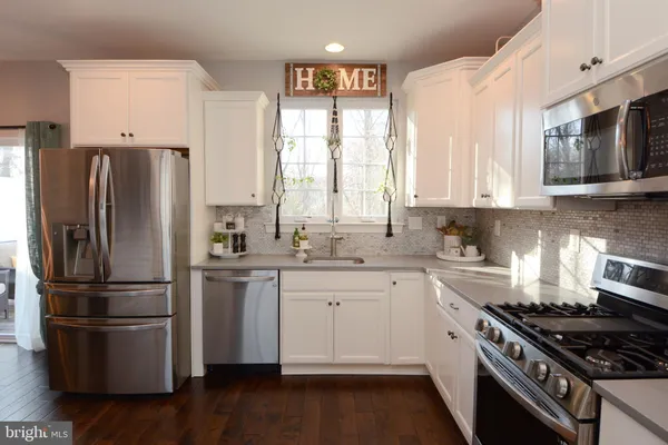 a large kitchen with kitchen island a large counter top space a sink stainless steel appliances and cabinets