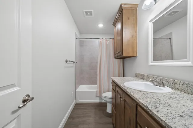 a bathroom with a granite countertop sink toilet and shower