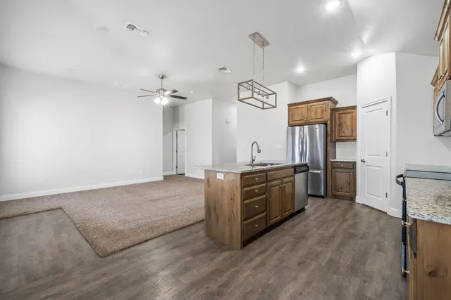 a large kitchen with stainless steel appliances a stove refrigerator and a sink