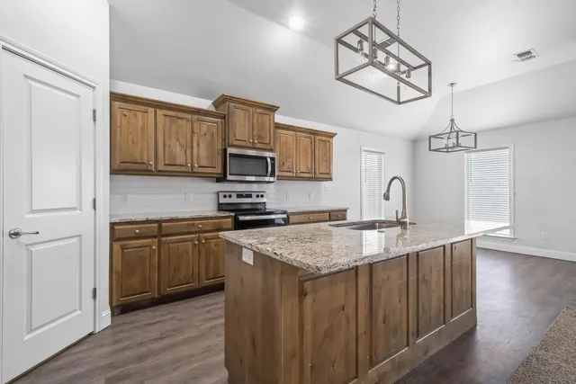 a kitchen with stainless steel appliances granite countertop a sink refrigerator and microwave