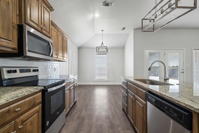 a kitchen with stainless steel appliances granite countertop a sink stove and cabinets