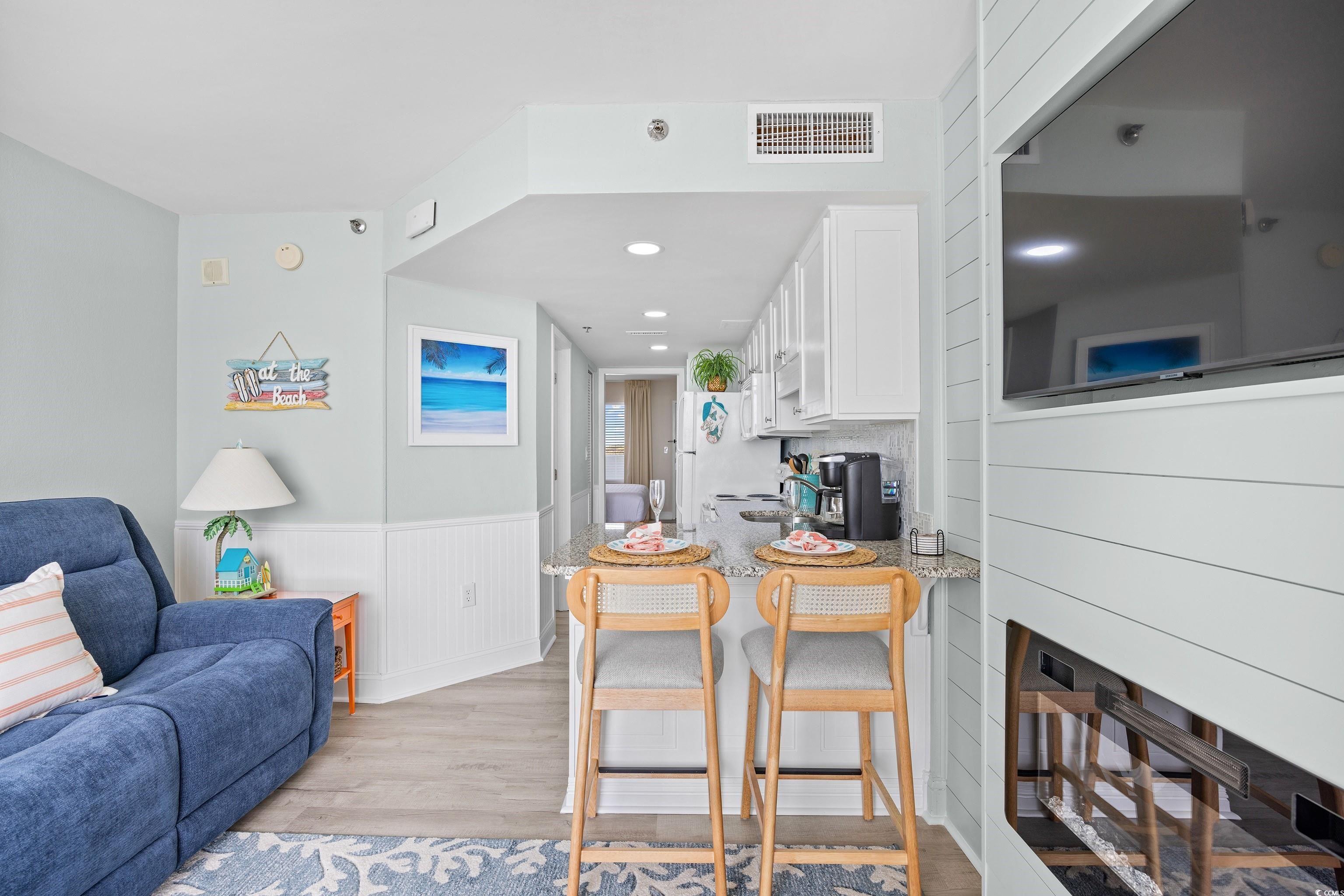 161 Seawatch Drive, Unit 1012 Myrtle Beach, SC 29572 - Photo 34 of 34 Kitchen with a kitchen breakfast bar, white cabinetry, light wood-style floors, open floor plan, and a wainscoted wall