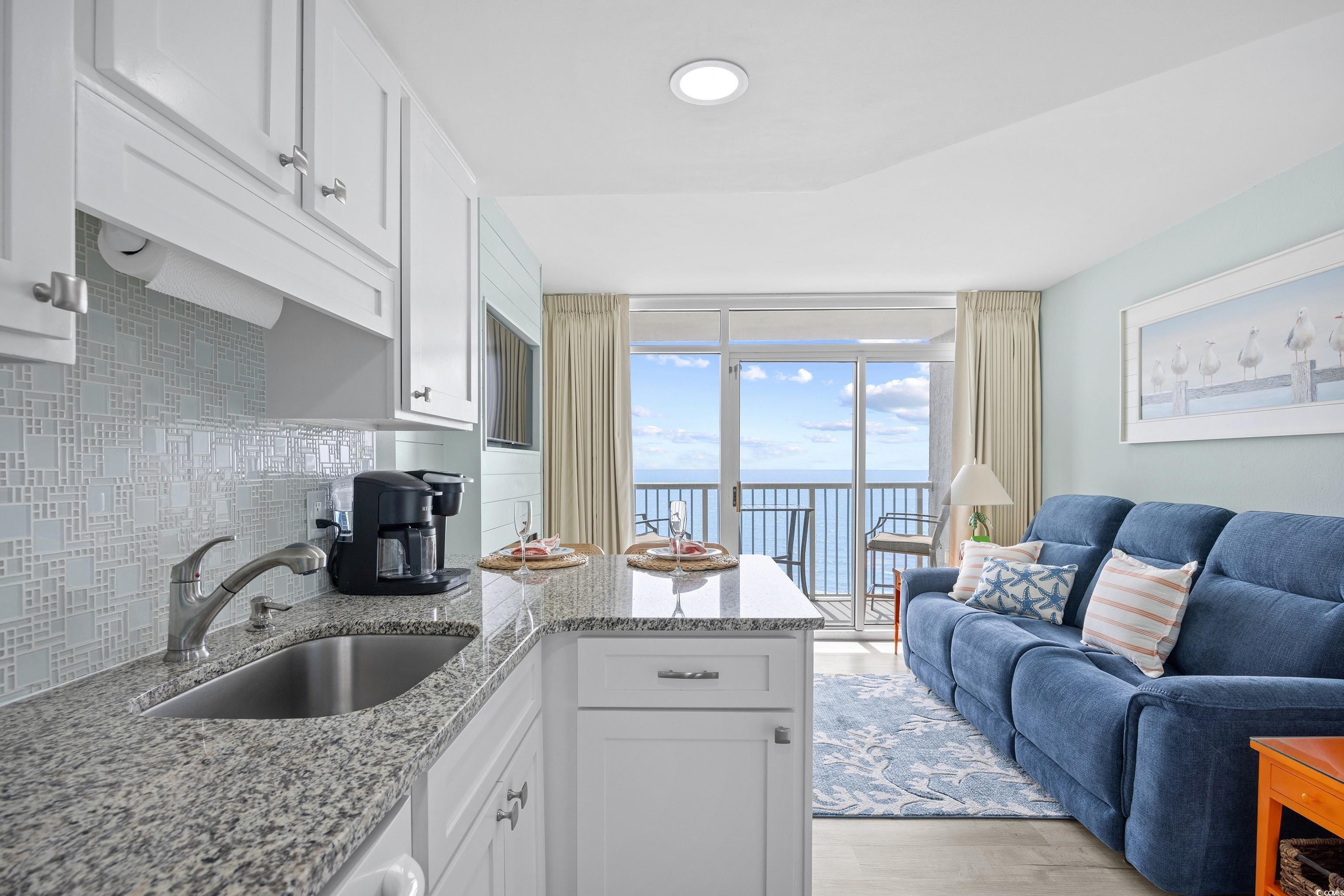 161 Seawatch Drive, Unit 1012 Myrtle Beach, SC 29572 - Photo 19 of 34 Kitchen featuring a peninsula, decorative backsplash, white cabinets, and a water view
