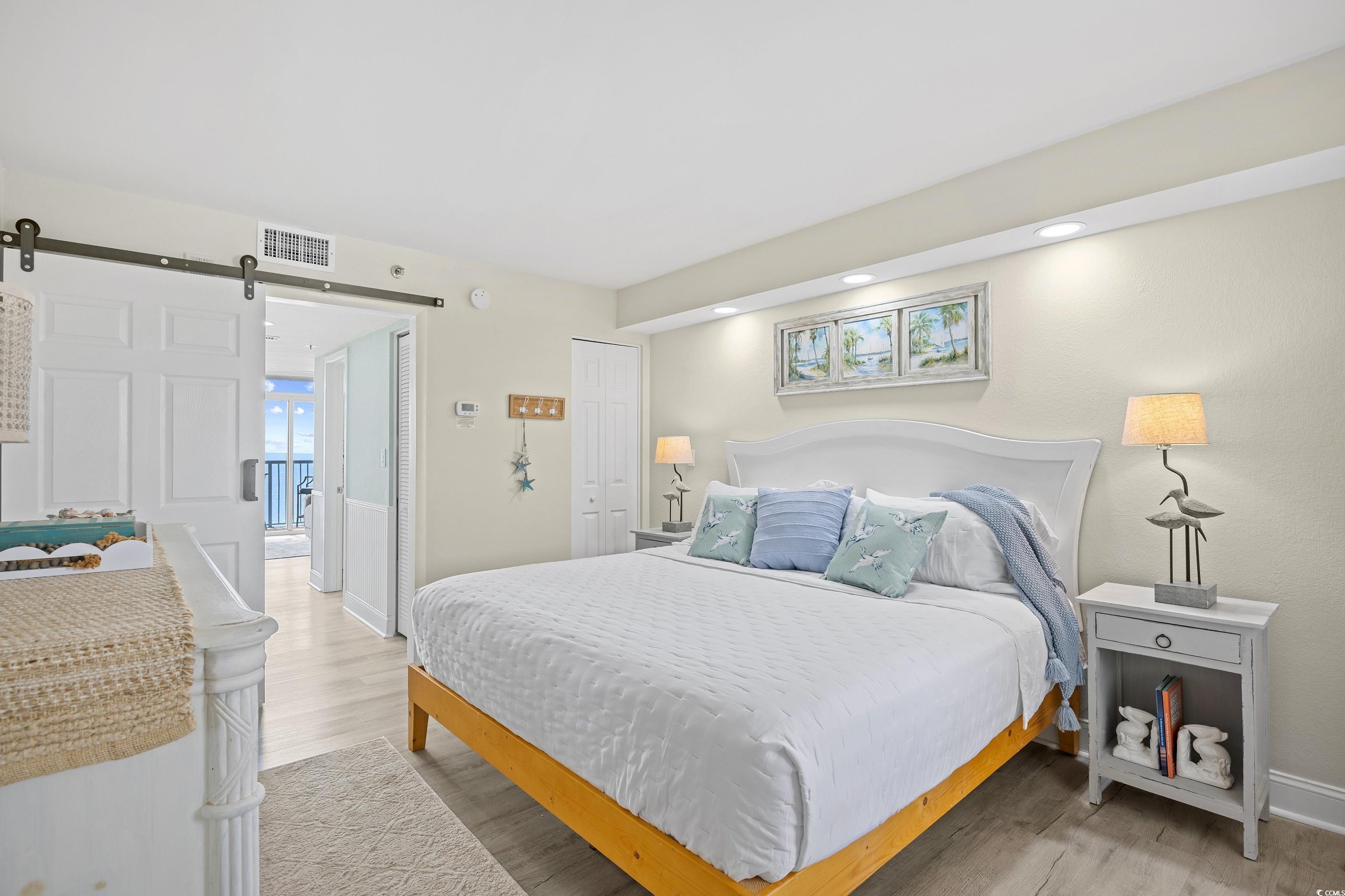 161 Seawatch Drive, Unit 1012 Myrtle Beach, SC 29572 - Photo 27 of 34 Bedroom featuring a barn door, light wood-style flooring, and a closet