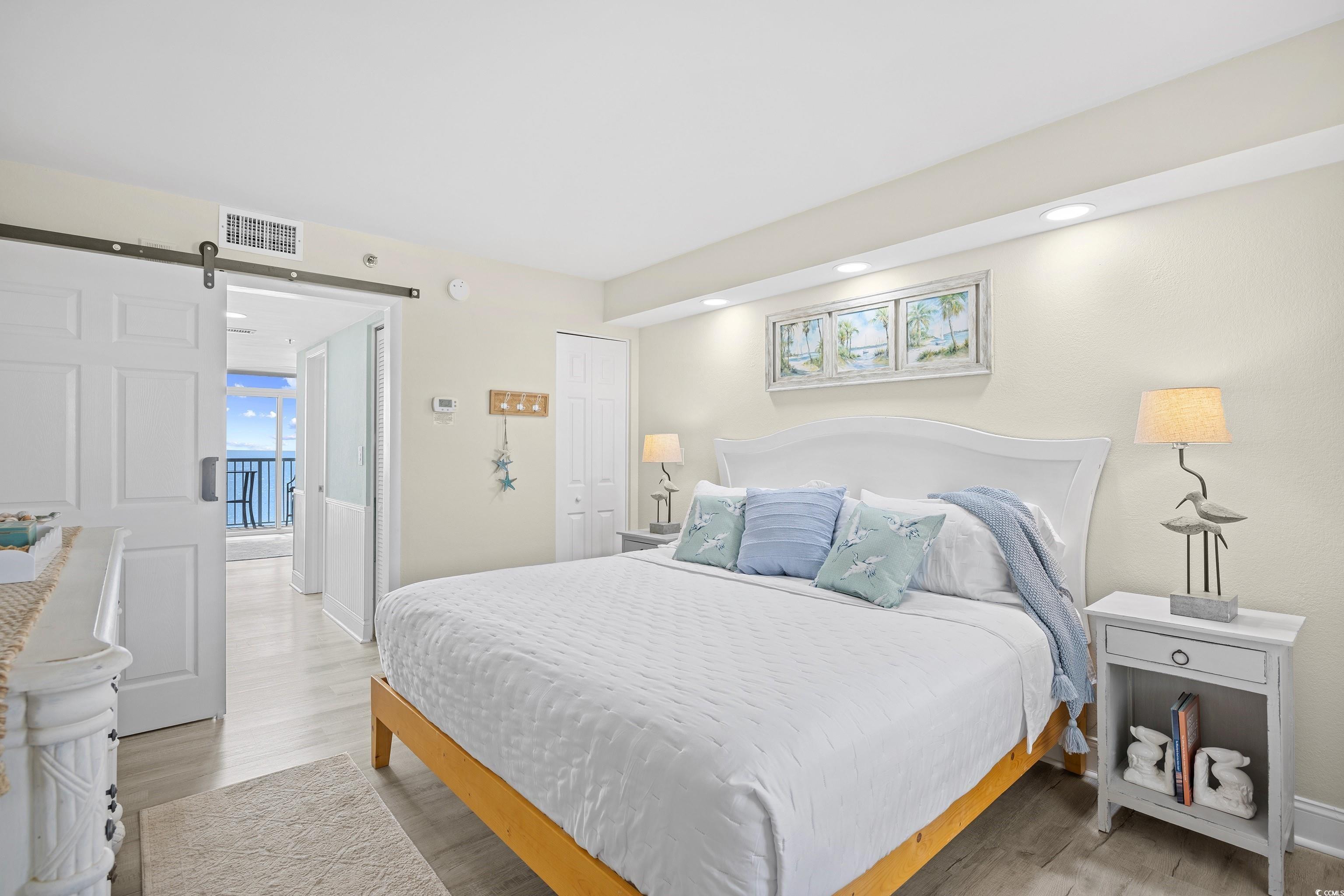 161 Seawatch Drive, Unit 1012 Myrtle Beach, SC 29572 - Photo 28 of 34 Bedroom featuring a barn door, light wood-style floors, a closet, multiple windows, and recessed lighting