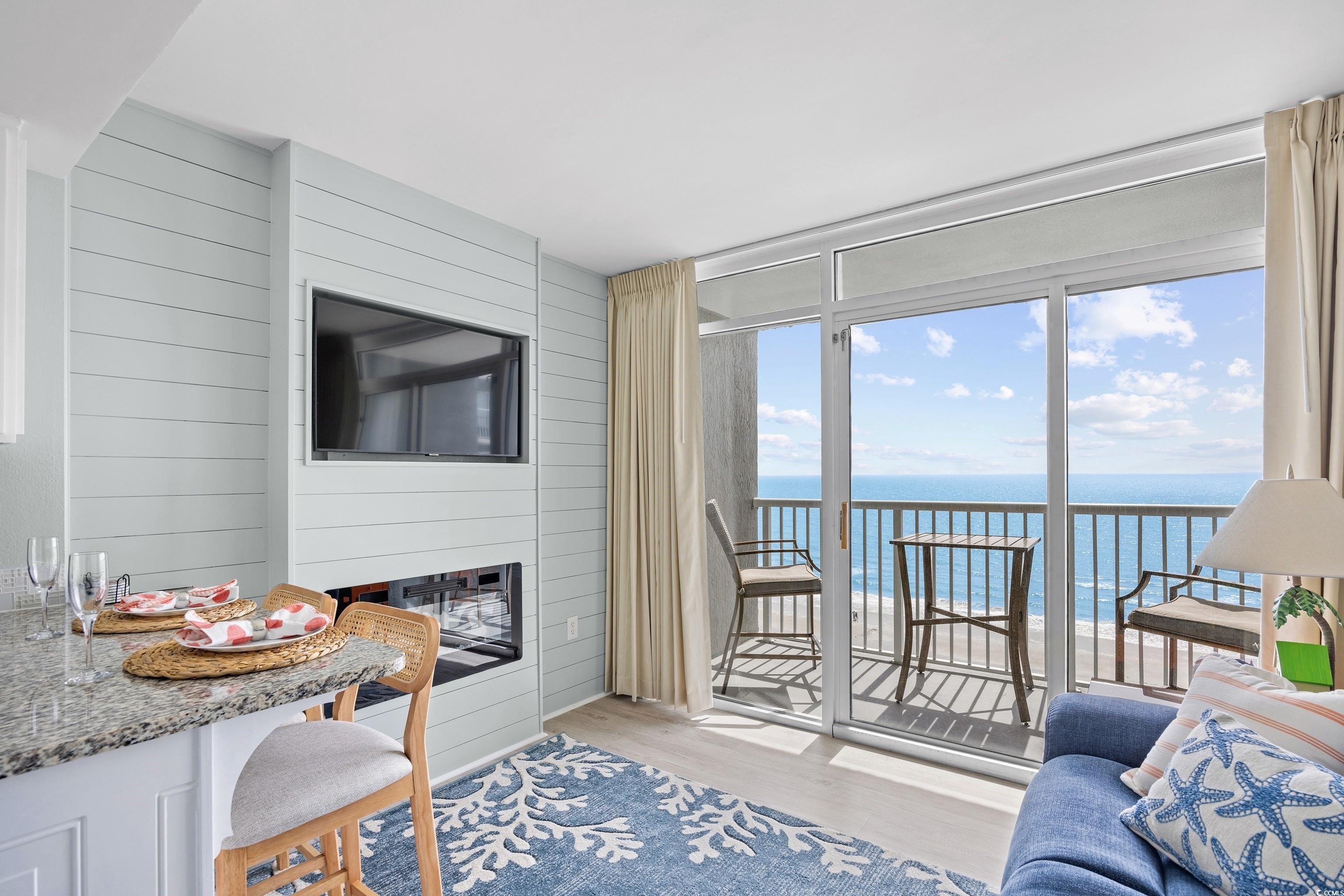 161 Seawatch Drive, Unit 1012 Myrtle Beach, SC 29572 - Photo 3 of 34 Living room with light wood-style floors, expansive windows, wood walls, and a fireplace