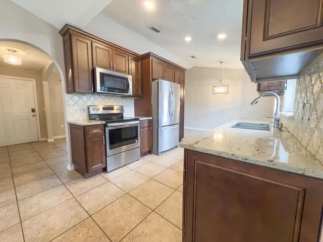 a kitchen with stainless steel appliances granite countertop a sink stove and refrigerator