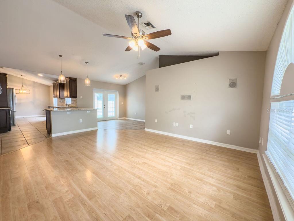 1723 Lochshyre Loop Ocoee, FL 34761 - Photo 7 of 23 an empty room with wooden floor a ceiling fan and kitchen view