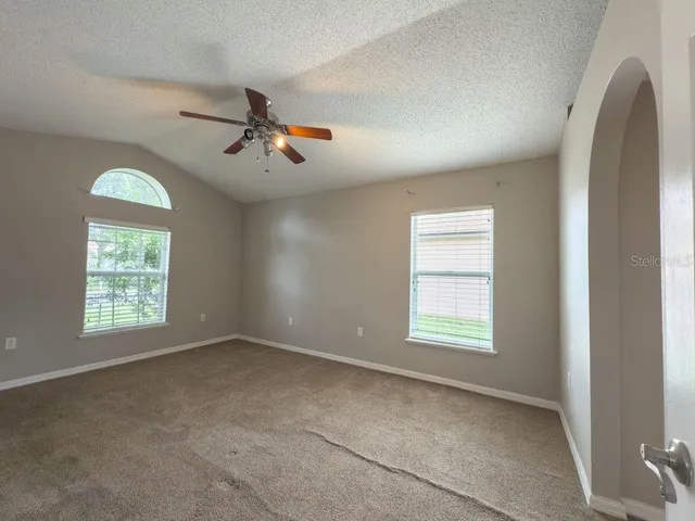 an empty room with windows and fan